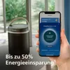 A person's hand is holding a smartphone next to a Philips air purifier. Podgląd zdjęcia produktu