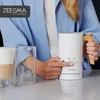 A person is using a white milk frother with a wooden handle next to two glasses. Produktbild-Vorschau