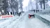 A rally car racing on a snowy track with spectators on the side. Produktbild-Vorschau