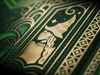 A close-up of a green and gold playing card box with intricate art deco designs. Náhled obrázku produktu