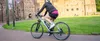 A person riding an e-bike in front of a stone building. Produktbild-Vorschau