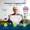 An older woman smiling and holding up an incontinence product. Produktbild-Vorschau