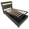 A bed frame with its mattress support mechanism lifted to reveal storage space underneath. The bed has a tufted headboard with integrated LED lighting. Voir les images du produit
