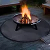 A round fire pit mat with a fire pit on it, set on a wooden deck. Produktbild-Vorschau