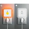 Two night lights plugged into wall outlets, one showing an orange glow and the other white. Produktbild-Vorschau