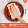 A hand is wiping a dirty pot with a paper towel. Produktbild-Vorschau