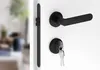A close-up shot of a black door handle and lock set on a white door. Produktbild-Vorschau