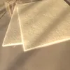 Two beige vacuum cleaner bags are stacked on a surface, with soft lighting casting shadows. Produktbild-Vorschau