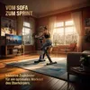 A woman is exercising on a stationary bike in a living room with a city view. Produktbild-Vorschau