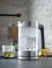 A glass electric kettle is boiling water on a kitchen counter, with a cup of tea and a lemon nearby. Anteprima dell’immagine prodotto