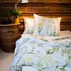A bed with floral patterned bedding in a rustic room. Produktbild-Vorschau