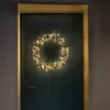 A circular wreath of warm white fairy lights is hung on a dark teal wooden door. Produktbild-Vorschau