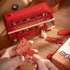 Hands assembling a wooden model of a red London double-decker bus. Anteprima dell’immagine prodotto