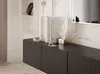 A close-up view of a black fluted TV stand with decorative items on top, including books and a white wing sculpture. Voir les images du produit