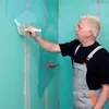 A man is applying a liquid to a wall with a brush. Produktbild-Vorschau