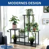 A multi-tiered black metal plant stand filled with various green plants, placed indoors near a window with sheer curtains. Podgląd zdjęcia produktu