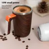 A self-stirring mug with coffee, surrounded by coffee beans and a pine cone in the background. Podgląd zdjęcia produktu