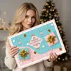 A woman holds an advent calendar in front of a Christmas tree. Produktbild-Vorschau
