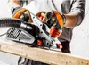 A person wearing work gloves is using an electric planer on a piece of wood. Náhľad obrázku produktu