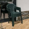 A stack of green plastic garden chairs is placed on a wooden deck next to a building with a stone accent wall. Náhled obrázku produktu