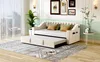 A beige upholstered daybed with a pull-out trundle bed is set up in a living room with a large window and decorative wall art. Anteprima dell’immagine prodotto