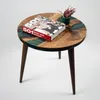 A round walnut and green epoxy resin side table with a book and a small plant on it, set against a white background. Produktbild-Vorschau