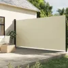 A beige retractable side awning is installed on a wooden deck next to a house, providing shade and privacy. Outdoor furniture and a coffee table are visible on the deck. Náhled obrázku produktu