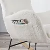 Close-up of a white, fluffy rocking chair with a magazine in the side pocket. Produktbild-Vorschau