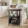 A kitchen scene featuring a black kitchen cart with a microwave and various kitchen items. Podgląd zdjęcia produktu