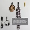Various hooks mounted on a wall, displaying items like a hat, headphones, keys, and a jacket. Produktbild-Vorschau