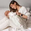 A woman is holding a baby wrapped in a swaddle. Produktbild-Vorschau