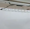The underside of a desk with a wire cable management tray attached, holding some cables. Produktbild-Vorschau