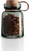 A glass storage jar filled with almonds, with a wooden lid and a leather strap. Voir les images du produit