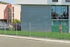 A metal fence in front of a modern building with a fire hydrant. Produktbild-Vorschau
