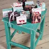 A collection of small, decorated boxes arranged on a teal-colored stool. Produktbild-Vorschau