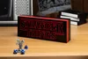 A Stranger Things logo light sits on a wooden desk, with a miniature figurine and dice in the foreground. Produktbild-Vorschau