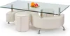 A modern coffee table with a glass top and a curved white base, featuring two round ottomans integrated into the base. Two grapefruits are placed on the table. Voir les images du produit