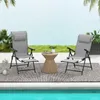 Two gray folding chairs with footrests and a small woven side table are set up on a rug next to a swimming pool. Produktbild-Vorschau