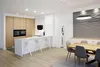 A modern kitchen and dining area with a white island, wooden cabinets, and a dining table. Produktbild-Vorschau