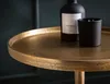 A close-up of a gold side table with a black bottle and a black candle on it. Podgląd zdjęcia produktu
