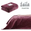 A folded blanket and a blanket draped over a bed. Produktbild-Vorschau