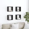 Four black cube-shaped wall shelves are mounted on a white wall above a light-colored sofa. The shelves contain decorative items. Produktbild-Vorschau