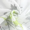 A close-up view of a white sheer curtain with a floral pattern in green and gray. Produktbild-Vorschau