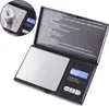A black digital scale with a silver weighing platform is shown, with instructions visible on the inside of the lid. An inset shows a weight placed on the platform. Produktbild-Vorschau