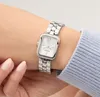 A woman's wrist wearing a silver Guess watch. Produktbild-Vorschau