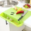 Limettenfarbenes Schneidebrett mit integrierter Seitenablage, die Knoblauch und Gemüseschalen hält, neben einem Messer, Paprika und Eiern auf einer Küchenarbeitsplatte Anteprima dell’immagine prodotto