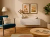 A living room scene with a teal armchair, a lowboard, artwork, and a coffee table. Produktbild-Vorschau