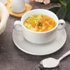 A bowl of chicken noodle soup with carrots and herbs, served on a saucer with a spoon nearby. Anteprima dell’immagine prodotto