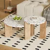 A set of two round coffee tables with terrazzo-style tops and wooden legs, placed on a patterned rug in a living room setting. Voir les images du produit