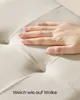 A hand pressing into a soft, beige fabric surface, with text overlay. Produktbild-Vorschau